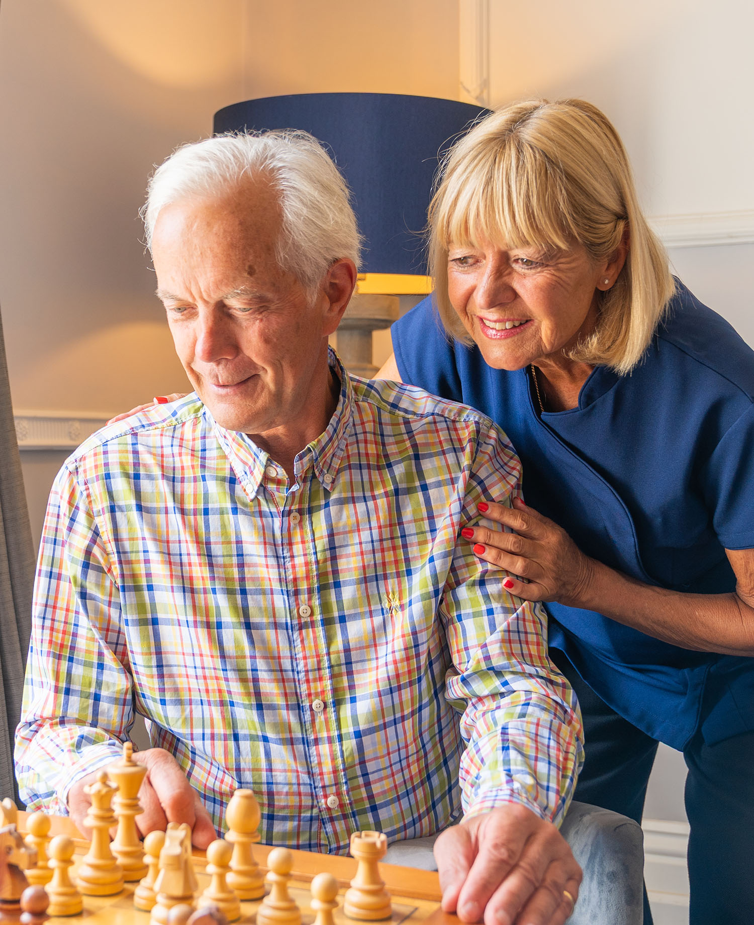 Resident playing chess alongside carer